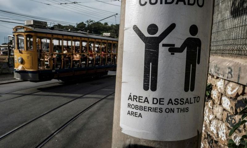 Rio's famous street car passes by a sign warning against robberies on an electricity pole in Santa Teresa, home to favelas where firefights between rival gangs and police are a common sight