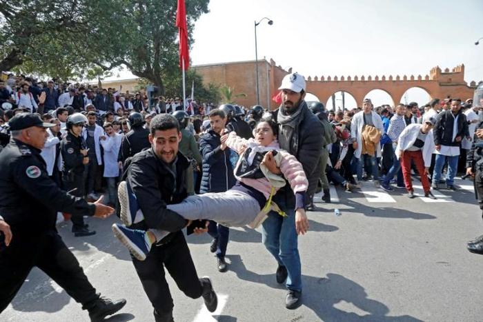 Moroccan public school teachers help a colleague who was injured in a scuffle with police during a demonstration in the capital Rabat on February 20, 2019