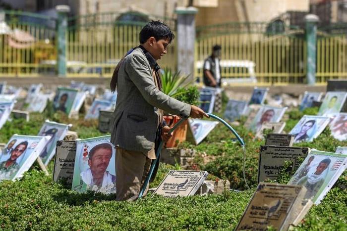 A Yemeni boy waters plants and cleans tombstones in a cemetery in the capital Sanaa on March 25, 2019