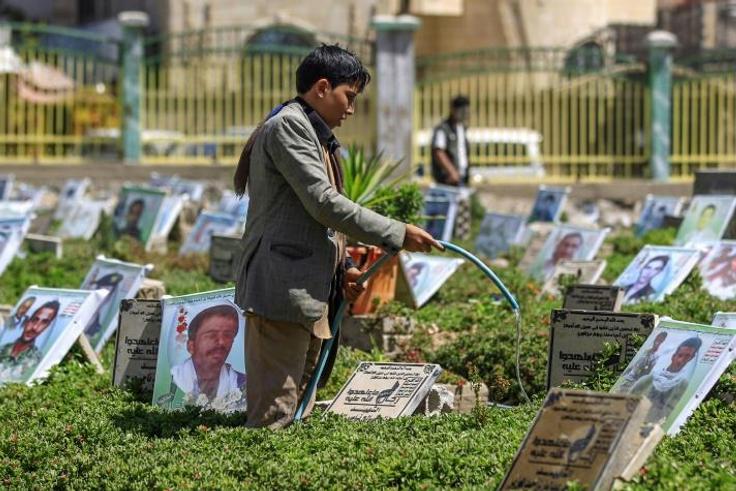 A Yemeni boy waters plants and cleans tombstones in a cemetery in the capital Sanaa on March 25, 2019