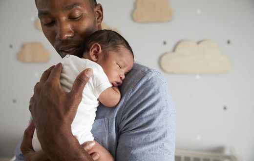 A daddy holding his new born baby.
