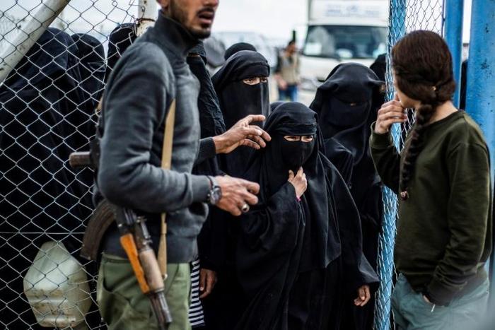 Members of the Syrian Democratic Forces stand guard over veiled women in al-Hol camp in northeastern Syria, which houses relatives of Islamic State group members