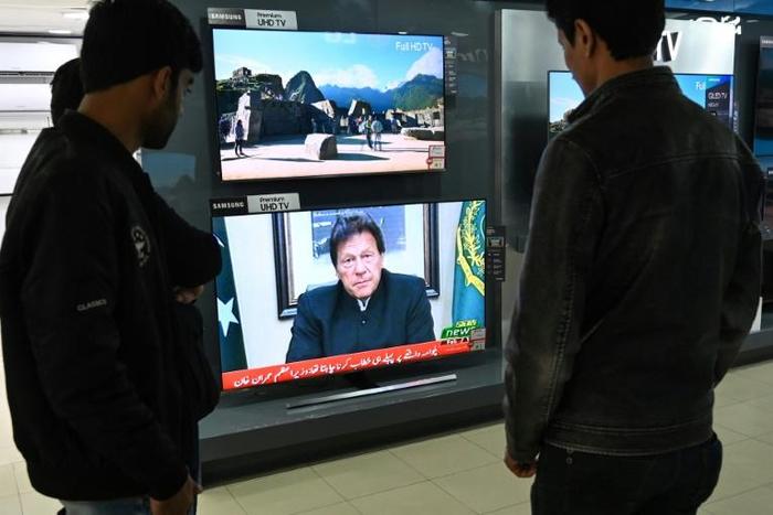 Islamabad residents watch on television as Pakistani Prime Minister Imran Khan addresses the nation
