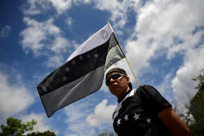A supporter of Venezuelan opposition leader Juan Guaido holds a black and white version of Venezuela's national flag during a rally in Caracas on May 11, 2019