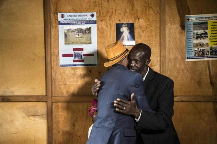 Jean-Bosco Gakwenzire, 65, of Tutsi ethnicity, embraces his old school mate Pascal Shyirahwamaboko (R), 68 with his wife Rose (hidden), both Hutu