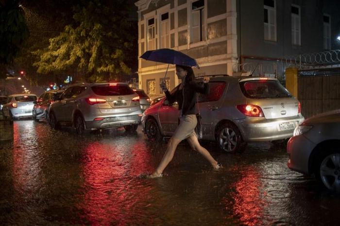 A woman crosses a street in Botafogo neighborhood in Rio de Janeiro, Brazil, as a downpour floods several areas of the city on April 8, 2019.