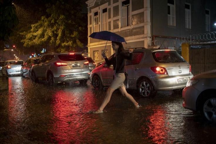 A woman crosses a street in Botafogo neighborhood in Rio de Janeiro, Brazil, as a downpour floods several areas of the city on April 8, 2019.