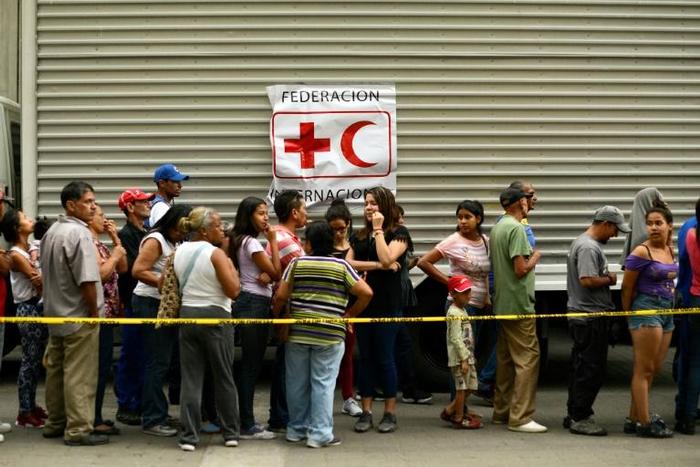 People queue to receive water drums and water purification tablets from the Red Cross in Caracas, Venezuela, on April 16, 2019, after the first shipment of Red Cross humanitarian aid arrived by plane from Panama