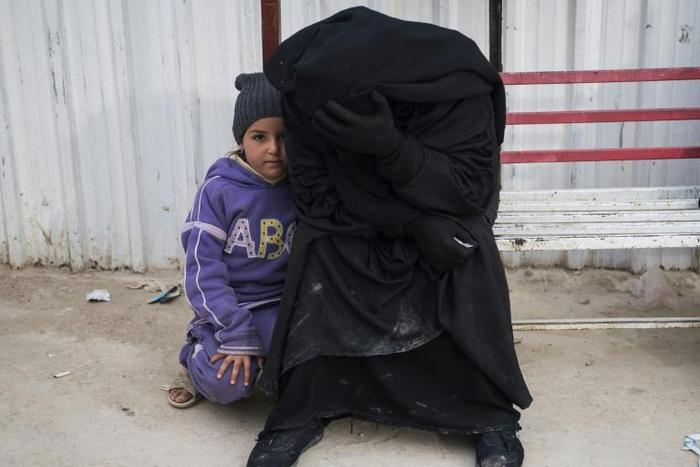 A Syrian woman and child wait at a camp for internally displaced people in al-Hol in northeastern Syria