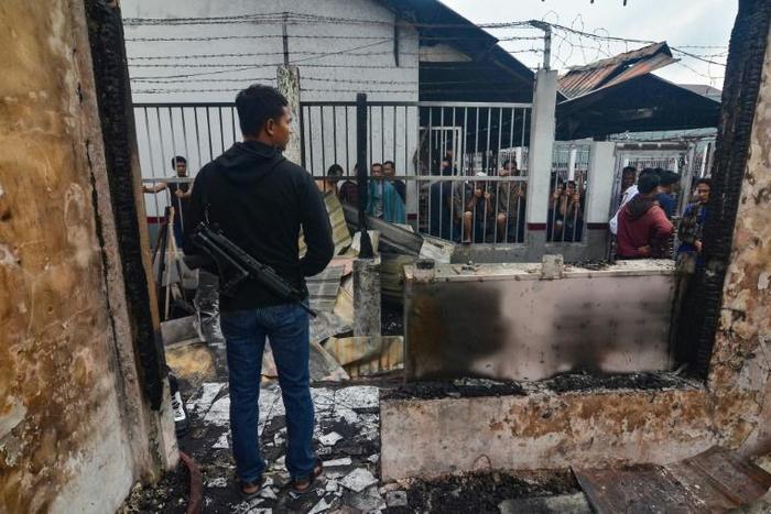 An armed plainclothes policeman at Siak prison after a riot and mass breakout