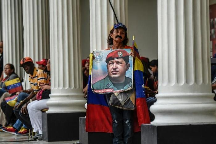 A supporter of Venezuelan President Nicolas Maduro holds a photo of his late predecessor Hugo Chavez at the National Assembly building in October 2017