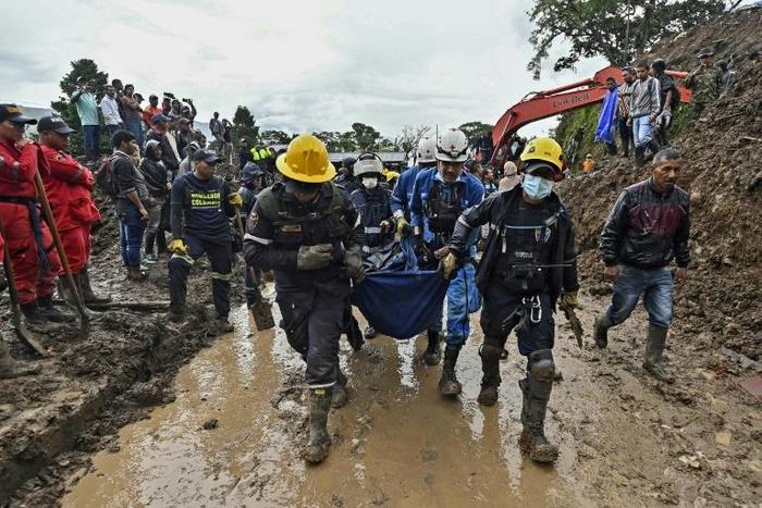 Firefighters carry away a dead body found under the mud in Rosas, southwest Colombia, following Sunday's mudslide provoked by heavy rains