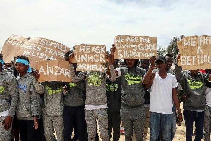Migrants hold placards during United Nations Secretary-General Antonio Guterres (unseen) visit to Ain Zara detention centre for migrants in the Libyan capital Tripoli on April 4, 2019