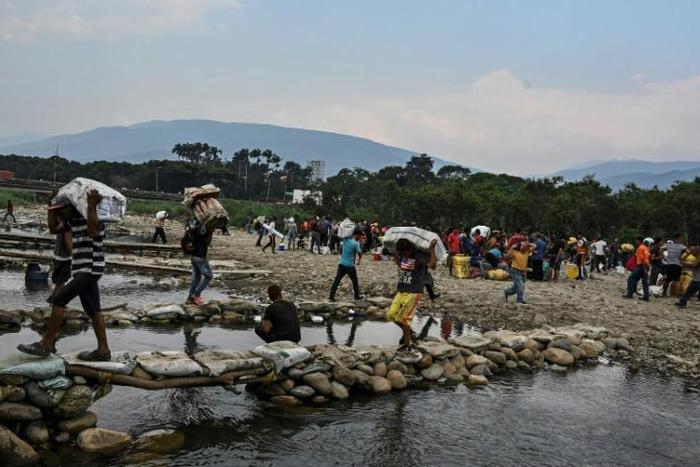 People carry goods along the "trochas" -illegal trails on the border between Cucuta in Colombia and San Antonio del Tachira in Venezuela, on April 13, 2019