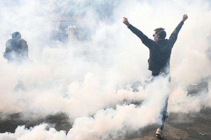 A protester raises his arms as French anti-riot police fire teargas as hardline anti-capitalist elements join Paris' annual May Day rally