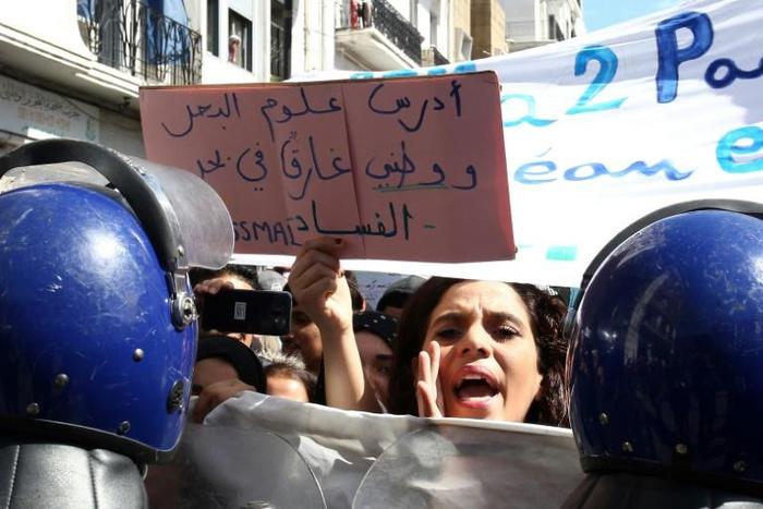 An Algerian protester holds sign that reads "My country is drowning in a sea of corruption"