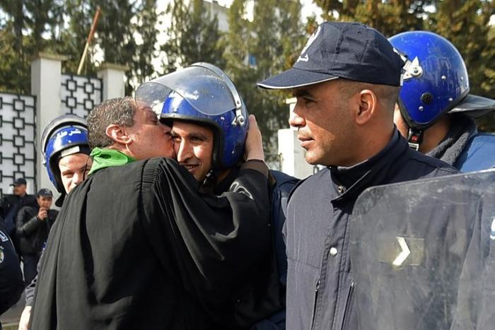 An Algerian lawyer kisses a policeman during a protest against ailing President Bouteflika's bid for a fifth term in power, in Algiers on Thursday