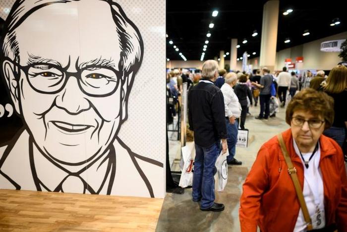 People pass an illustration of Warren Buffett, CEO of Berkshire Hathaway, during the 2019 annual shareholders meeting in Omaha, Nebraska