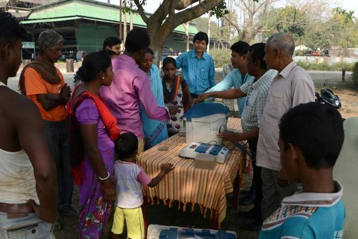 An Indian election official explains the procedure to cast a ballot to voters at a tea estate near Siliguri, West Bengal