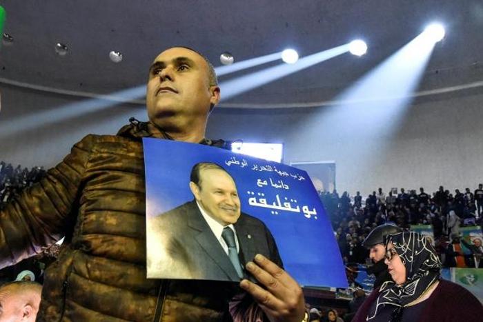 A supporter of Algeria's National Liberation Front holds up a poster of President Abdelaziz Bouteflika during a pre-campaign party rally in Algiers on February 9, 2019