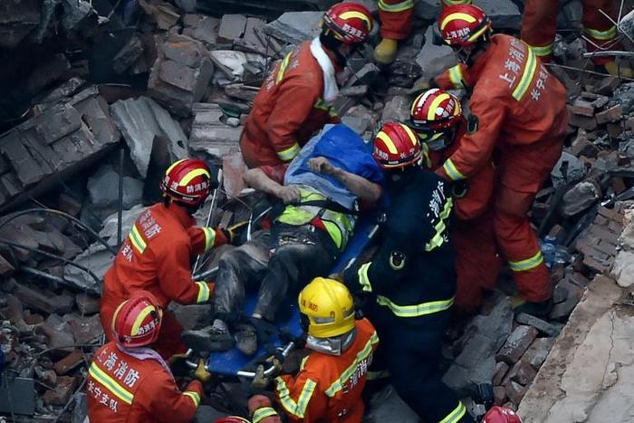 About half of the low-rise building collapsed in Shanghai, crushing construction workers under piles of toppled concrete pillars and shattered wooden beams