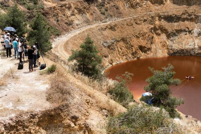 Journalists look on as Cyprus forensic police officers investigating the murder of seven women and girs search a lake outside Mitsero village, southwest of the capital Nicosia on April 30, 2019