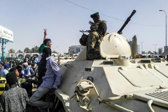 Sudanese protesters salute soldiers in front of the military headquarters in the capital Khartoum