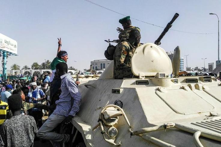 Sudanese protesters salute soldiers in front of the military headquarters in the capital Khartoum