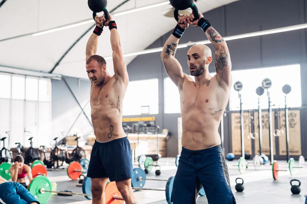 Men weightlifting with kettle bells in gym