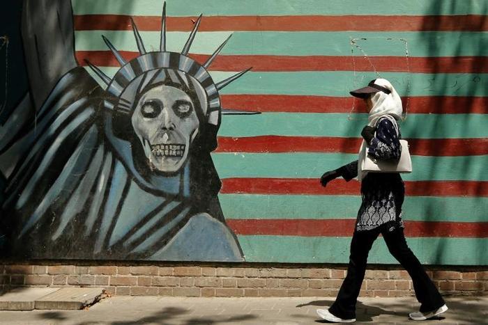 An Iranian woman walks past a mural depicting the Statue of Liberty, painted on the wall of the former US embassy in the capital Tehran on August 7, 2018