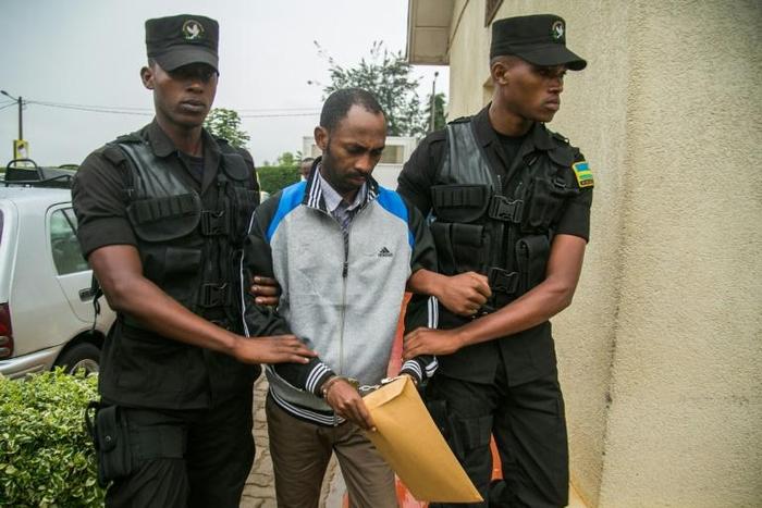 Callixte Nsabimana, spokesman for the National Liberation Front (FLN), was escorted by police officers into the court in Kigali