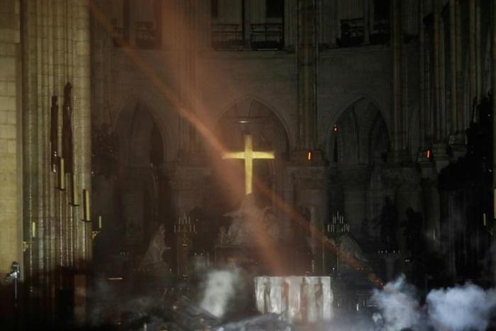 Smoke rises around the alter in front of the cross inside the Notre-Dame Cathedral in Paris as firefighters continued to extinguish the blaze on Tuesday