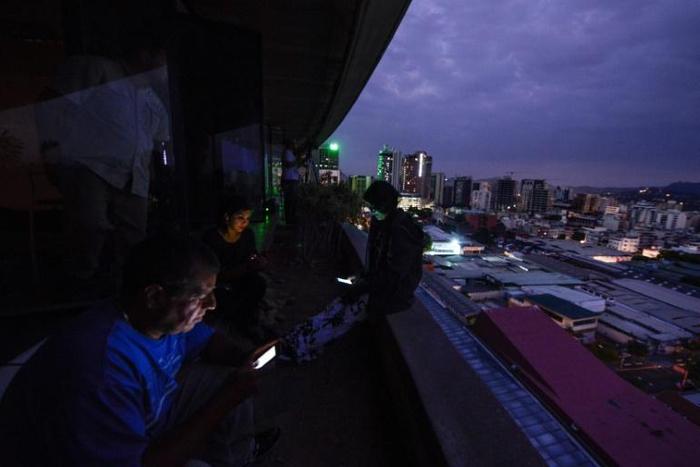 Journalists use cell phones during a huge blackout in Venezuela