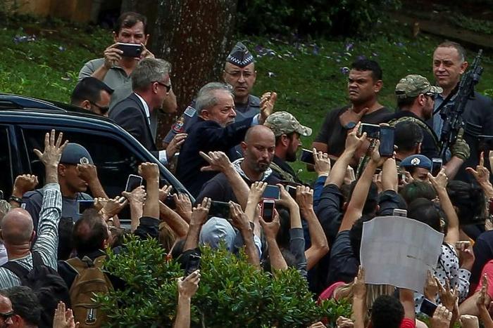 Brazilian former president (2003-2011) Luiz Inacio Lula da Silva (C-waving) is escorted by security forces upon arrival at Jardim da Colina cemetery to attend the funeral of his grandson on March 2, 2019