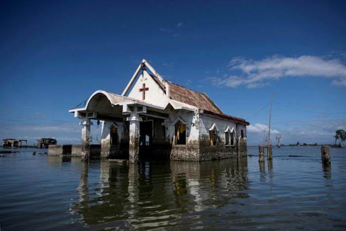 Twenty years ago the residents of Sitio Pariahan could walk to the local chapel but today reaching it requires a swim, because the town, like many in the Philippines, is sinking