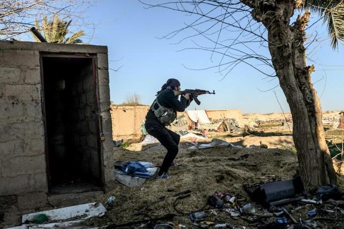 A fighter with the Syrian Democratic Forces (SDF) takes aim with his Kalashnikov assault rifle after seeing a man walking towards his position in the town of Baghouz, in the eastern Syrian province of Deir Ezzor, on March 9, 2019