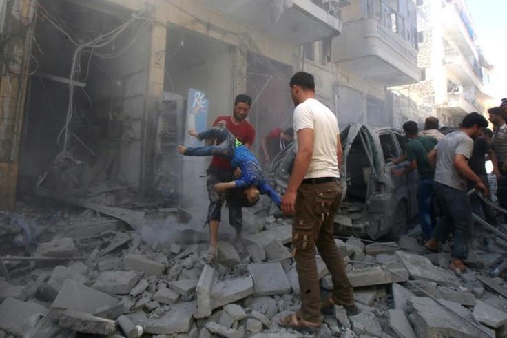 A man evacuates a young casualty following a reported air strike by regime forces and their allies in the jihadist-held Syrian town of Maaret Al-Numan in Idlib province on Sunday