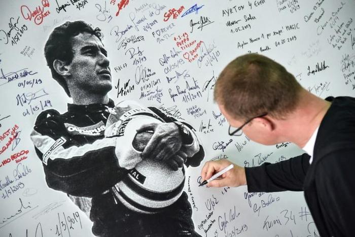 A man signs a poster of Brazilian's F1 driver Ayrton Senna during a ceremony on May 1, 2019 marking the 25th anniversary of the death of Brazilian's F1 driver Ayrton Senna during the 1994 San Marino Grand Prix