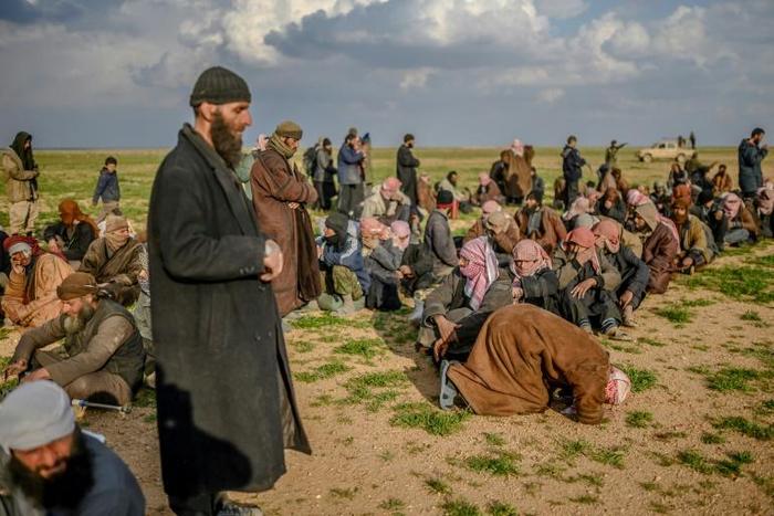 A man prays as men suspected of being Islamic State (IS) fighters wait to be searched by members of the Kurdish-led Syrian Democratic Forces (SDF) in Syria's northern Deir Ezzor province, on February 22, 2019