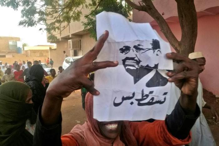A Sudanese protester carries a portrait of President Omar al-Bashir with Arabic writing that reads "down and that is all" during an anti-government demonstration east of the capital Khartoum on February 8, 2019