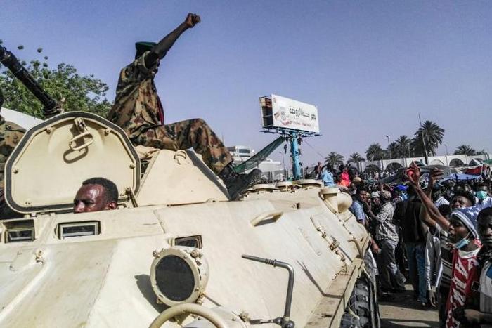 Sudanese protesters salute a military armoured vehicle at a demonstration in front of the army headquarters in Khartoum, as some ranks appear to be tiling towards the rallies