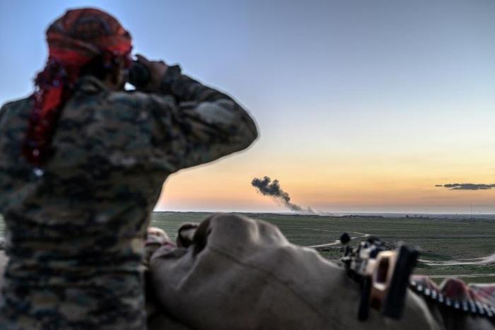 A Syrian Democratic Forces fighter watches the village of Baghouz where the Islamic State group has its last sliver of territory