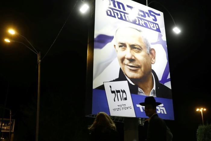 A woman and an ultra-Orthodox Jewish man walk past a billboard displaying Israeli Prime Minister Benjamin Netanyahu in Jerusalem
