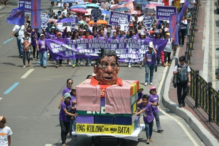 Activists push a carriage with an effigy of Philippines' President Rodrigo Duterte as they march toward Malacanang palace to commemorate International Women's Day in Manila