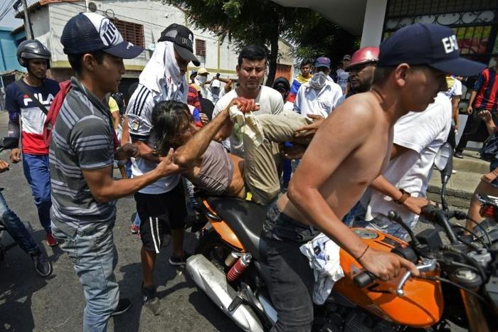 Protesters in the Venezuelan border town of Urena carry off a person wounded in a demo demanding to cross into Colombia seeking aid