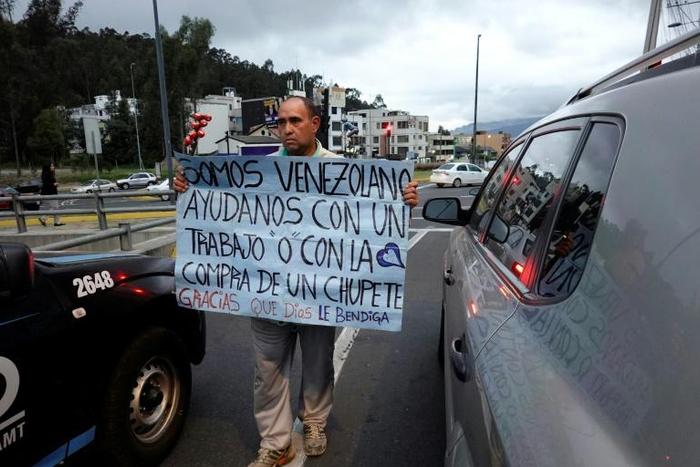 A Venezuelan living in Ecuador -- one of the millions from his country who have fled an economic meltdown -- holds a sign asking for a job or for people to buy one of his lollipops, on a street corner in Quito, Ecuador, in January 2019