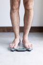 Man weighing self on bathroom scale
