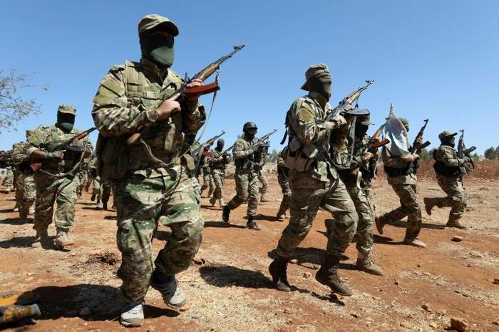 Fighters take part in a graduation ceremony for new Hayat Tahrir al-Sham (HTS) members at a camp in Syria's northern Idlib province