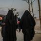 Veiled women, reportedly wives and members of the Islamic State group, walk under the supervision of a female fighter from the Syrian Democratic Forces at al-Hol camp in northeastern Syria