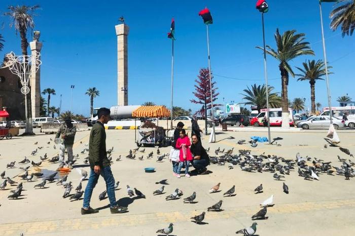Libyans walk in the Tripoli's Martyr Square as fresh fighting flared south of the capital